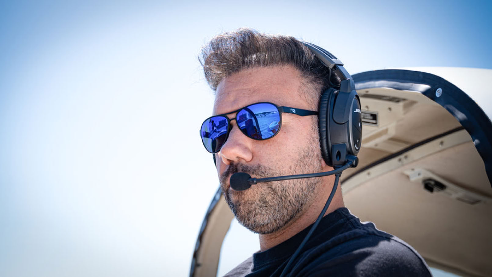 Man met Flying Eyes zonnebril en headset, zittend in een vliegtuig.